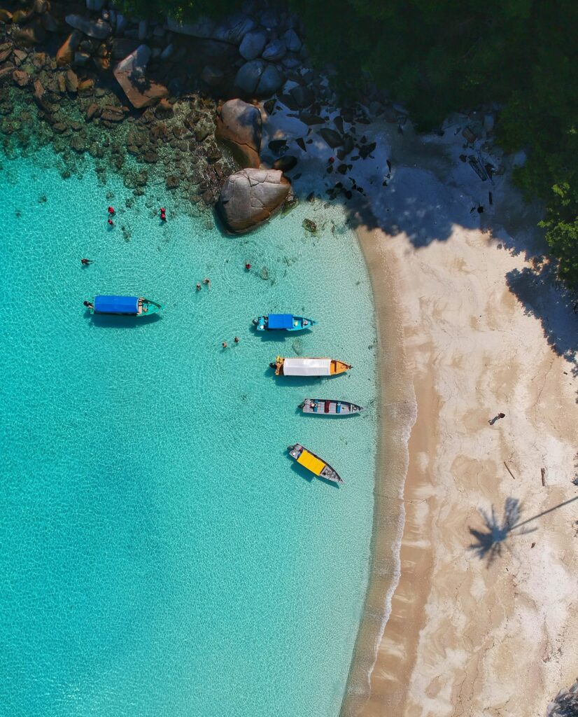 Vista aérea de una playa de aguas turquesa con botes